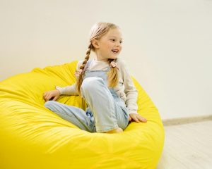 girl in white long sleeve shirt sitting on yellow bean bag