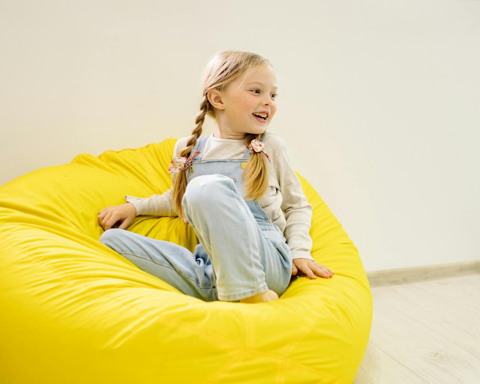 girl in white long sleeve shirt sitting on yellow bean bag