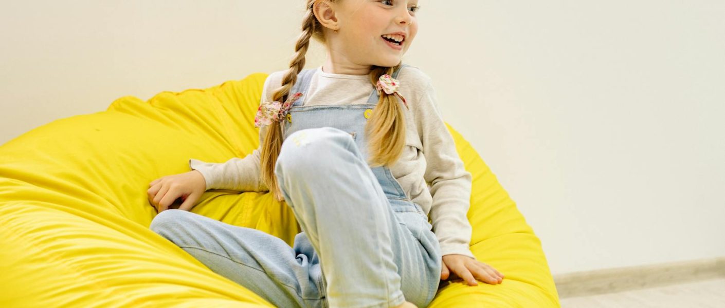 girl in white long sleeve shirt sitting on yellow bean bag