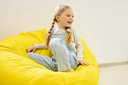 girl in white long sleeve shirt sitting on yellow bean bag