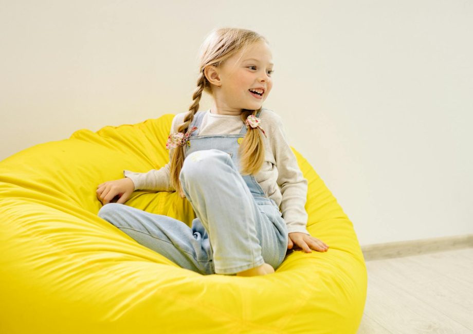girl in white long sleeve shirt sitting on yellow bean bag